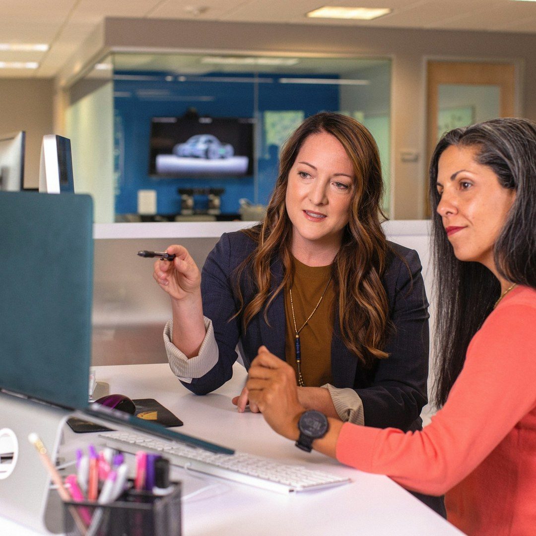 Two colleagues reviewing work together at a desk